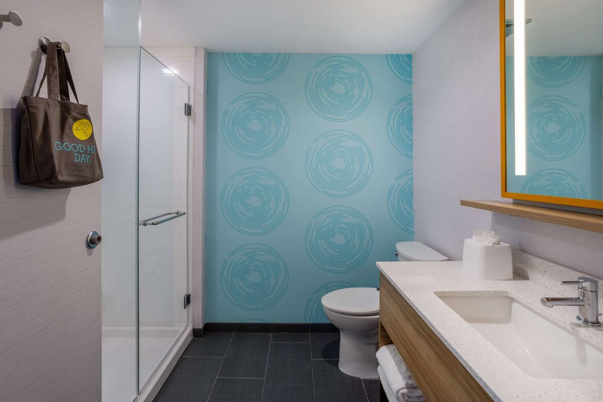 Une salle de bain moderne avec une douche en verre, des toilettes et un lavabo avec un miroir au-dessus.
