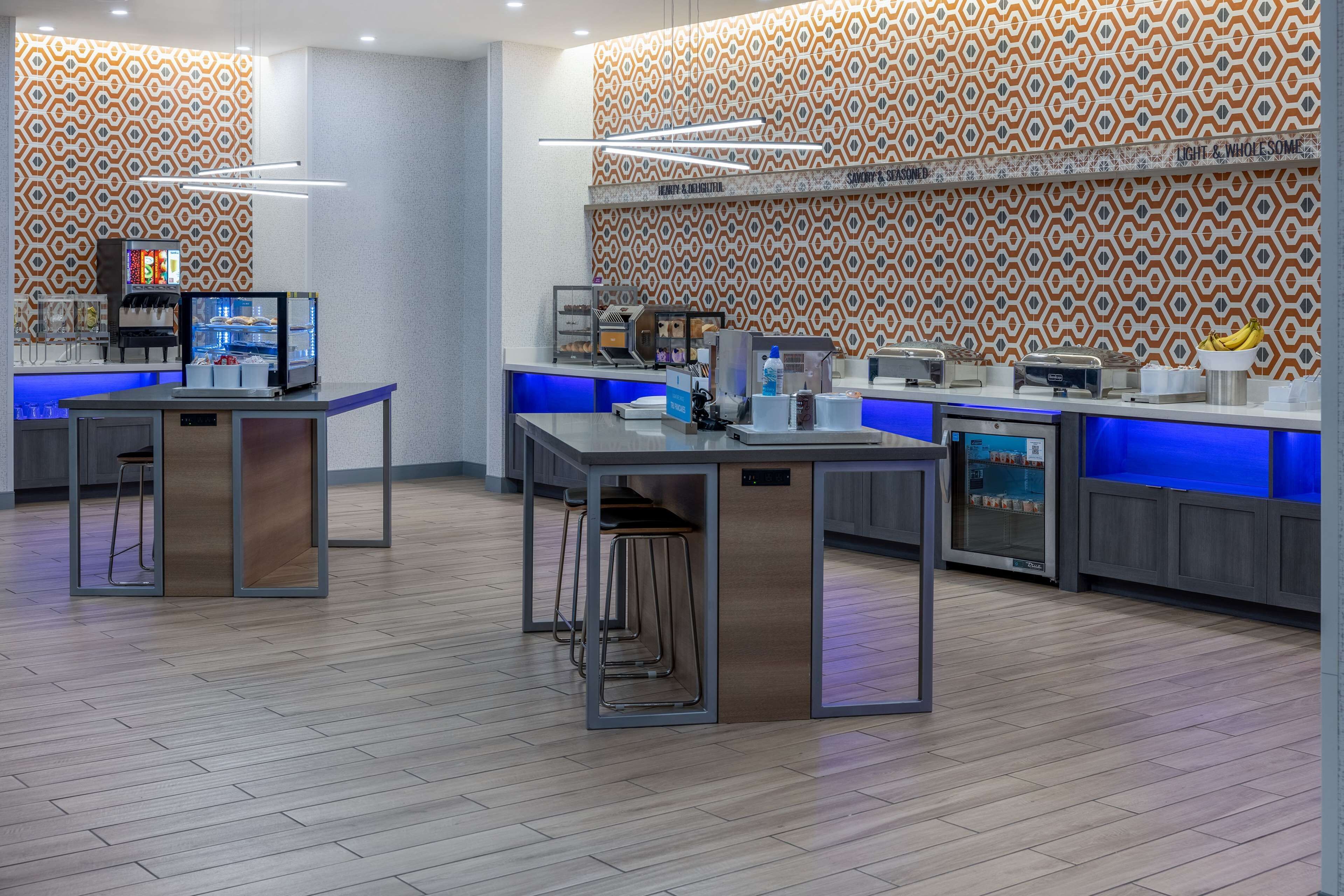 A modern kitchen area with bar stools, a coffee machine, and a display case.
