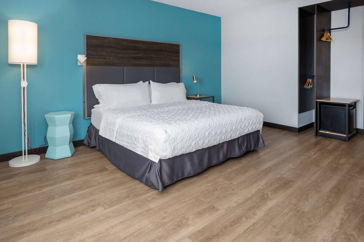 Une chambre moderne avec un grand lit, une table de chevet, une lampe sur pied et une armoire intégrée.