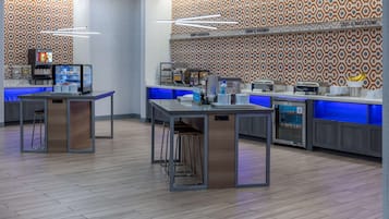 A modern cafe with a patterned wall, a digital menu display, and a counter with stools.