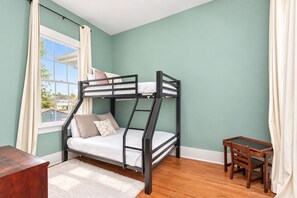 Un lit superposé dans une chambre aux murs de couleur turquoise, avec un plancher en bois et une petite table.