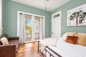 Une chambre à coucher avec un lit, un canapé, une fenêtre avec des rideaux et une porte.