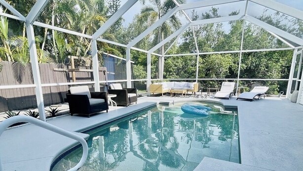 Una piscina exterior techada con sillas de descanso y un jacuzzi.