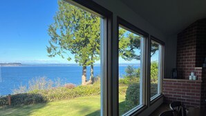 Quarto com grandes janelas com vista para uma área gramada e um corpo d'água.
