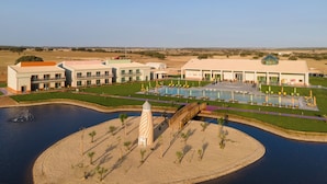 Vue aérienne d’un complexe hôtelier doté d’une piscine, d’un pont et d’une petite île avec une fontaine.