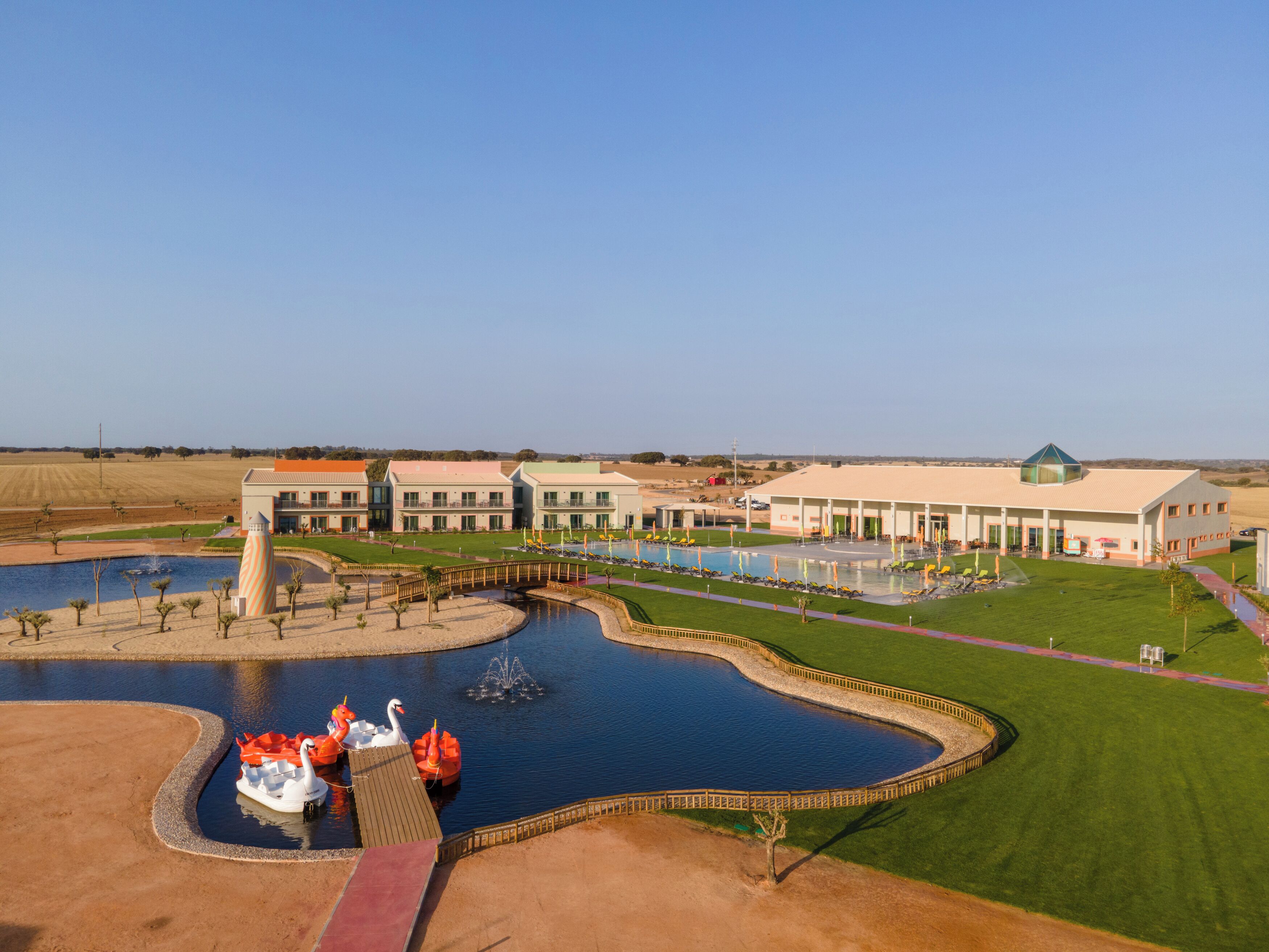 A large hotel with a swimming pool, a bridge, and a fountain.