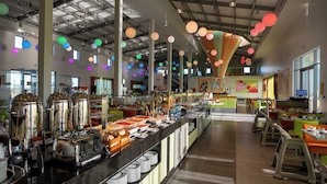 Un espace buffet proposant différents stands de restauration, un bar à café et des espaces aménagés pour s'asseoir.