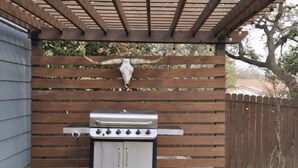 Una parrilla para barbacoa con un gabinete metálico, frente a una valla de madera con un adorno de cráneo de vaca.