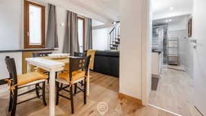 A modern kitchen with a dining area, wooden flooring, and a staircase leading to an upper level. - Modern Gem in Castello (Cagliari)