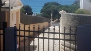 A coastal view from a balcony with a metal railing, a street in the background, and a clear sky. - Villa beach (VC)