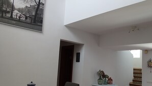 A spacious living area with a high ceiling, a dining table with chairs, a bench, a staircase, and a decorative vase on a cabinet. - Villa beach (VC)