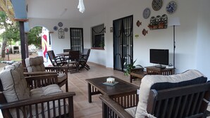 A spacious living area with a dining table, chairs, sofas, and a TV. - Villa beach (VC)