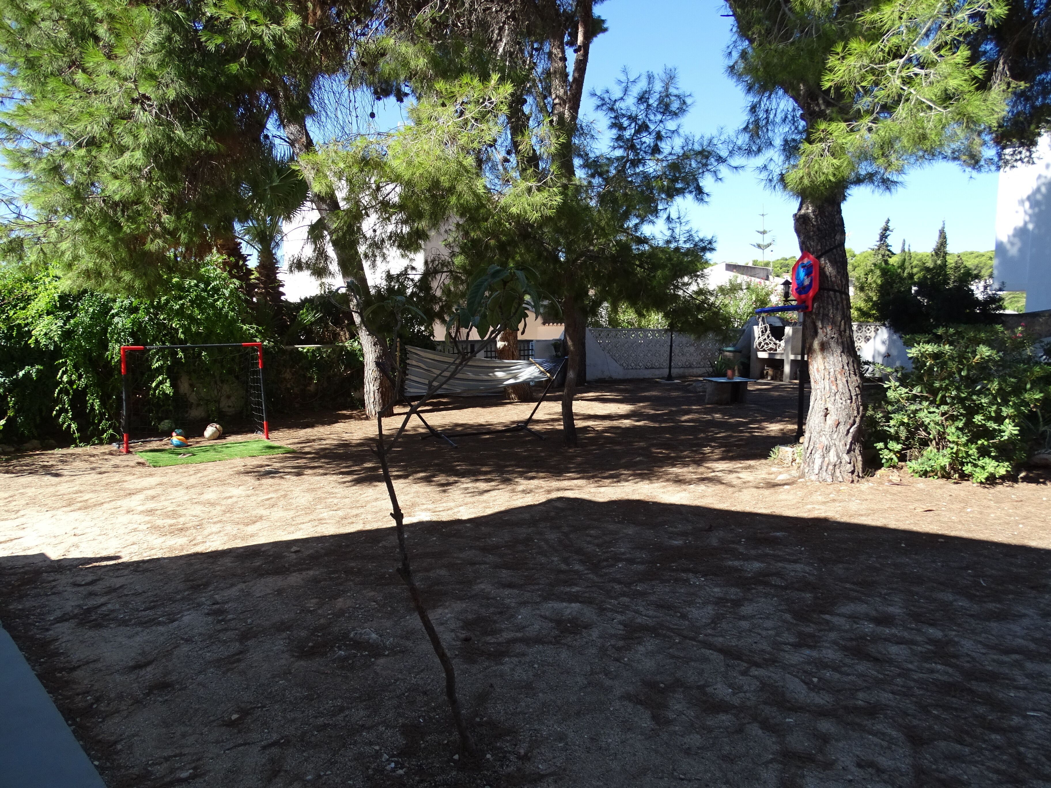 A backyard with a hammock, a soccer goal, and a barbecue area.