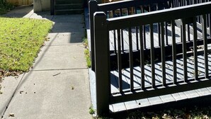 Ett tvåvåningshus med en veranda framtill, en inglasad uteplats och ett trästaket.