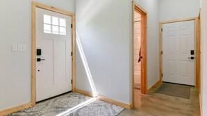 A hallway with white walls, wooden doors, and a patterned rug. - Lakefront Retreat w/Views, Fire Pit & 2 Acres (Golden)