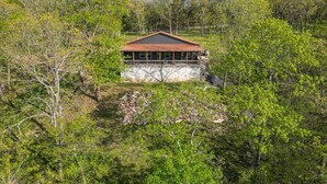 A single-story building with a flat roof, surrounded by dense greenery and trees. - Lakefront Retreat w/Views, Fire Pit & 2 Acres (Golden)