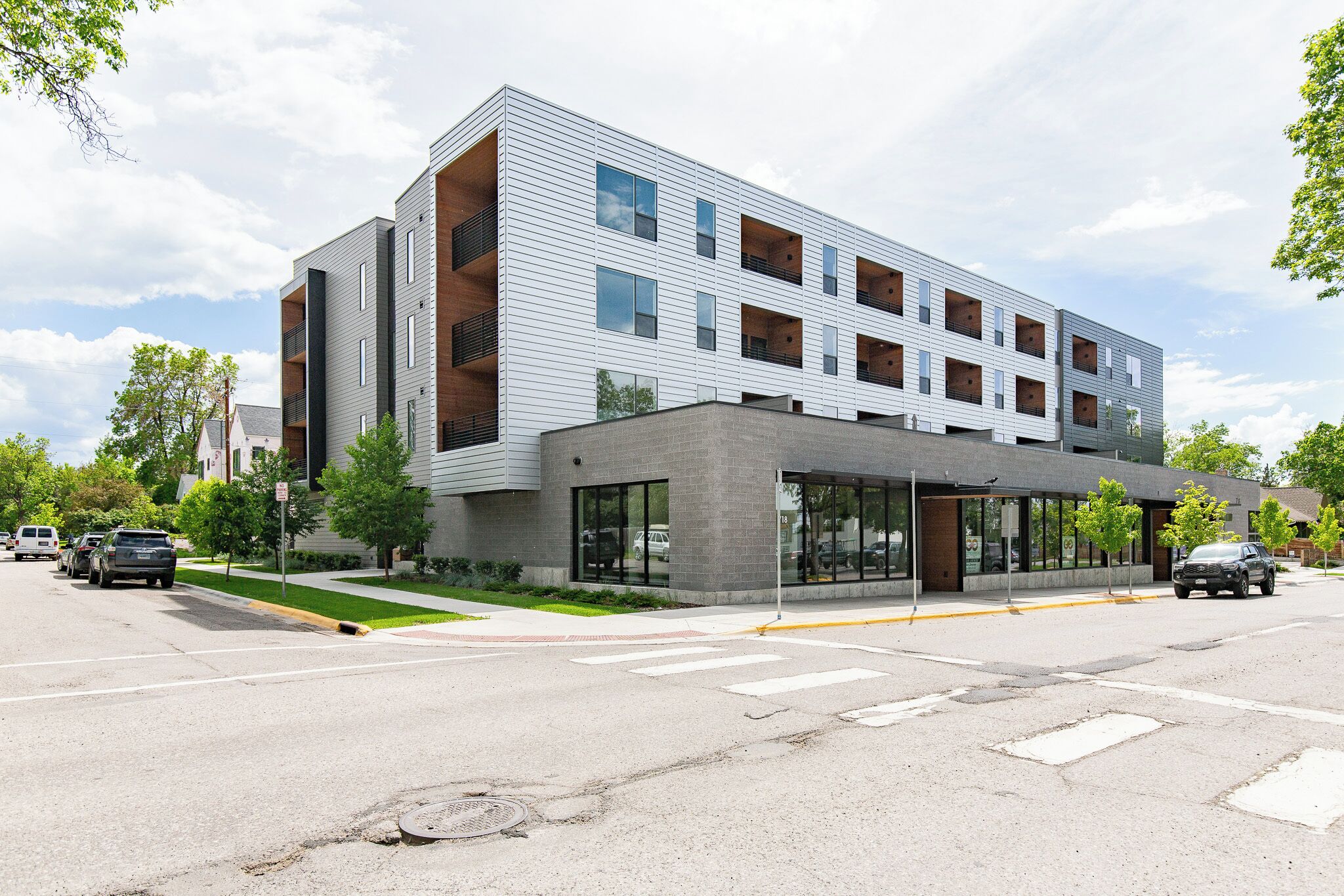 A modern multi-story building with a flat roof, large windows, and a covered entrance area.