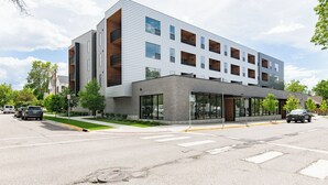 A modern multi-story building with a flat roof, large windows, and a covered entrance area.