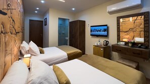 Une chambre d’hôtel avec deux lits, une télévision, un minibar et un mur orné de hiéroglyphes égyptiens.