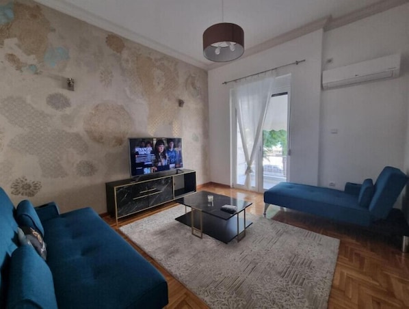 Un salon avec un téléviseur, un canapé bleu et une table basse.