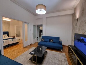 Un espace de vie compact comprenant un canapé, un téléviseur et une petite table.