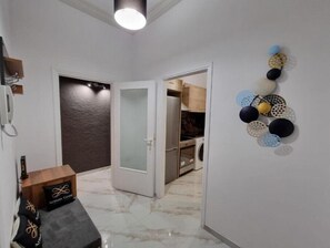 Un couloir doté d’un sol en marbre, d’une porte blanche et d’un mur orné d’œuvres d’art décoratives.