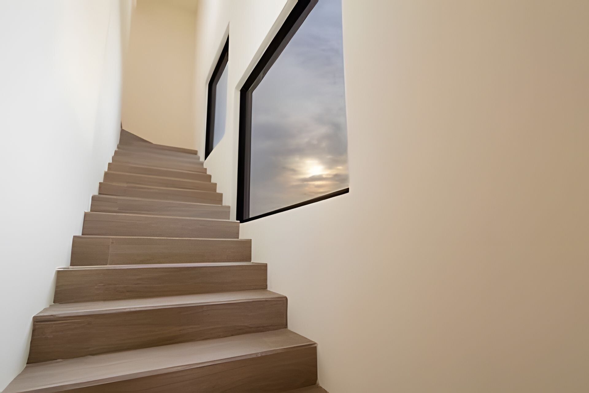 A modern staircase with wooden steps and a glass panel on the right.
