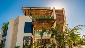 A modern building with a flat roof, large windows, and a sign indicating a location. - Moots Tulum (Tulum)