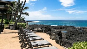 A beachside seating area with lounge chairs and a view of the ocean.
