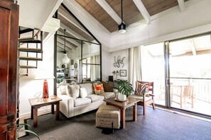 Relax in this stylish living room with a high ceiling, sliding glass door to a balcony, and comfortable sofa set.