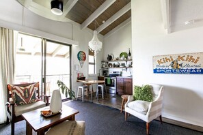 Relax in this spacious living area with a high ceiling and large window, featuring a comfortable seating area and kitchenette.