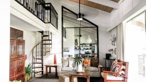 A spacious living room with a staircase, a sofa set, a coffee table, and a bookshelf.