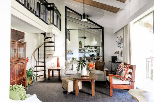 A spacious living room with a staircase, a sofa set, a coffee table, and a bookshelf.