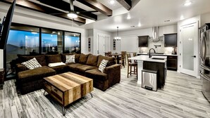 A modern living room with a sectional sofa, wooden coffee table, and a dining area with chairs. - Modern Accessorized 3-Bedroom (Las Cruces)
