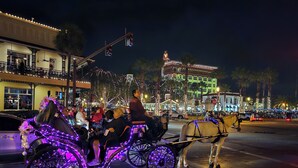 Un carruaje tirado por caballos con ruedas iluminadas y un caballo, conducido por una persona, en una calle por la noche.