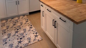 A modern kitchen with white cabinets, a wooden countertop, and a built-in dishwasher.