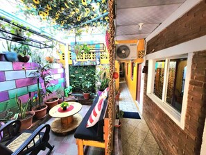 A narrow corridor with a bench, potted plants, and a colorful brick wall. - LEYENDAS (León)