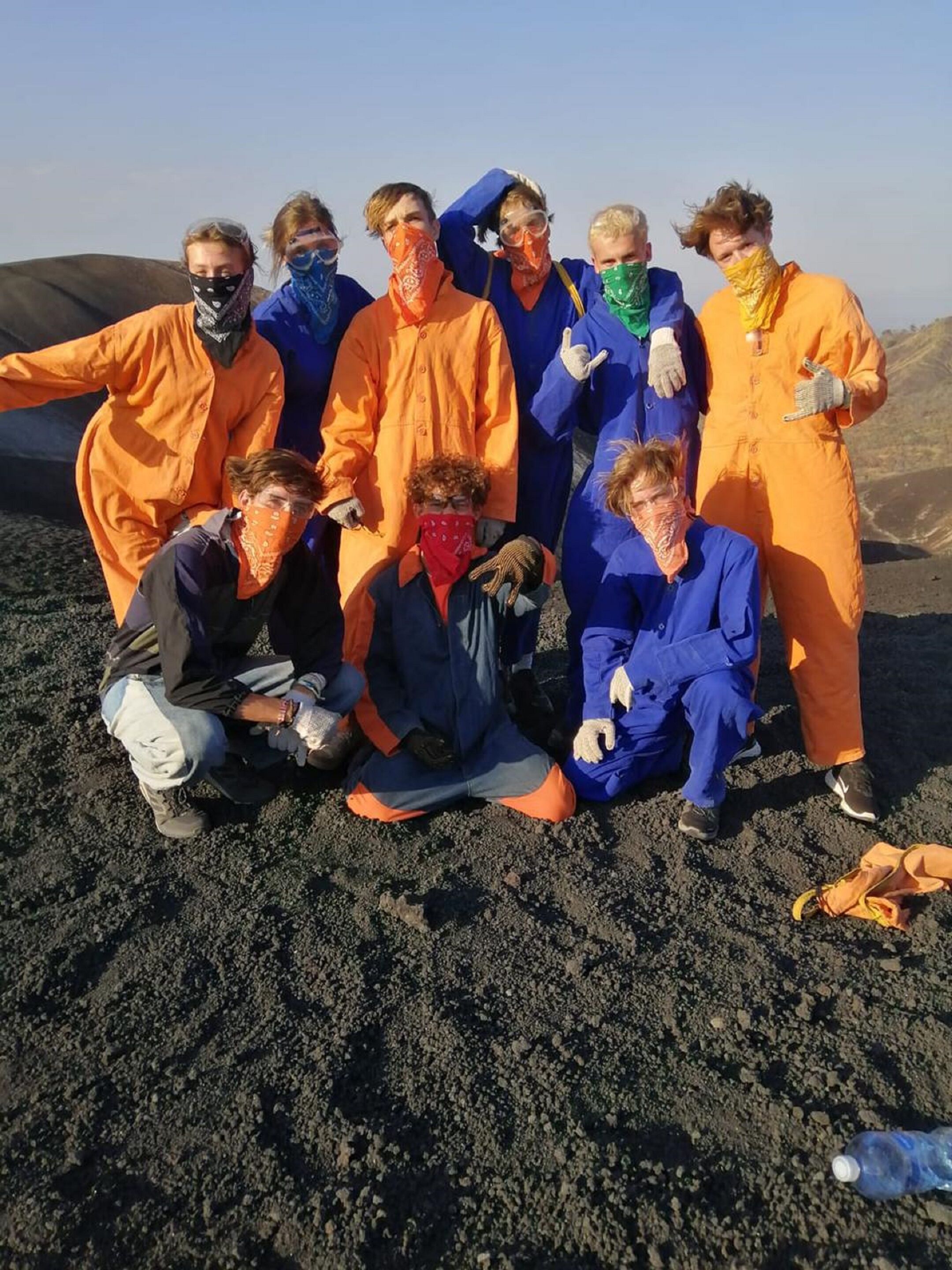 Eine Gruppe von Personen in orangen und blauen Schutzanzügen posiert auf einer felsigen Fläche.