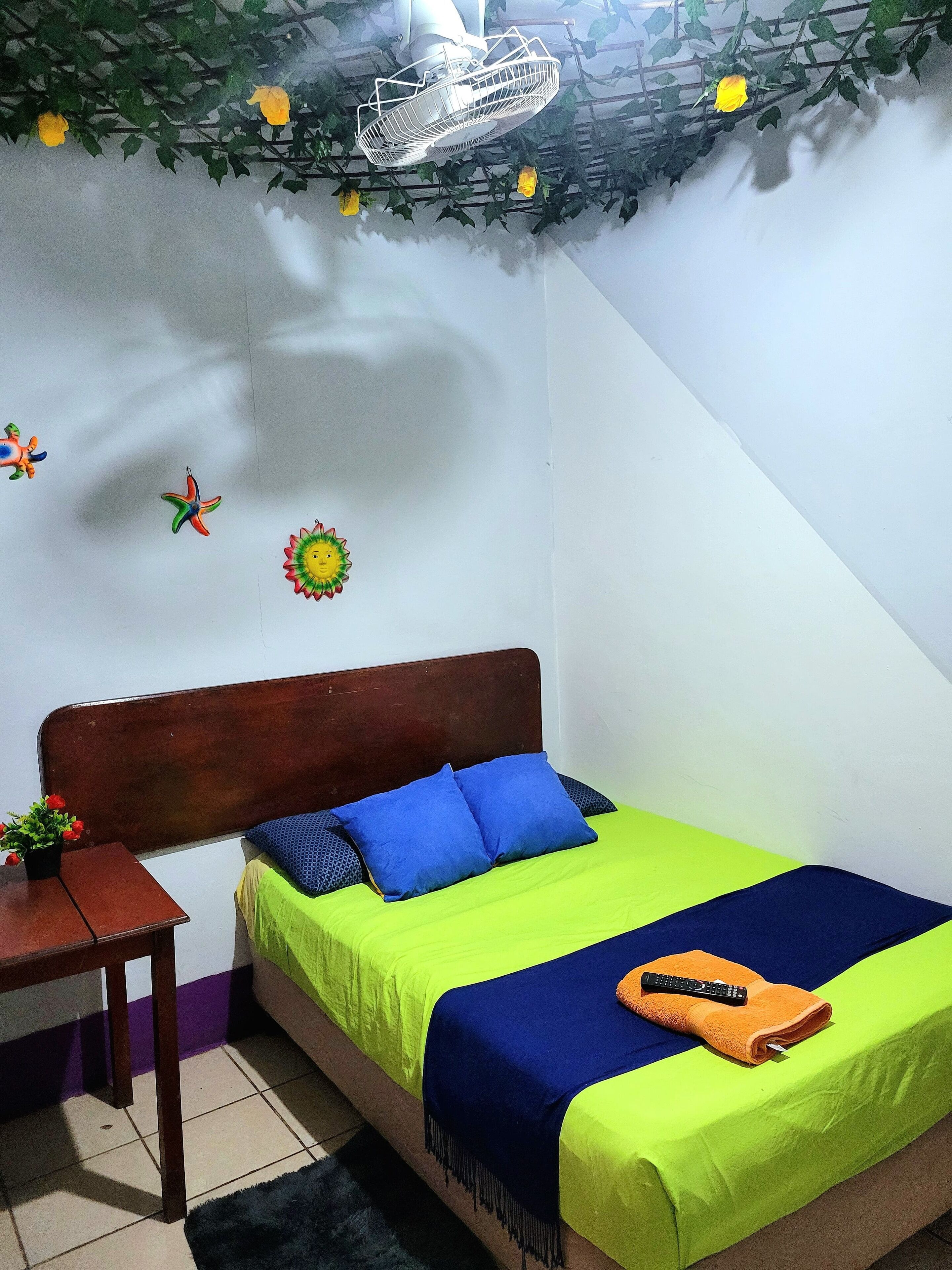 A small, neatly arranged bedroom with a bed, a nightstand, and a ceiling fan.