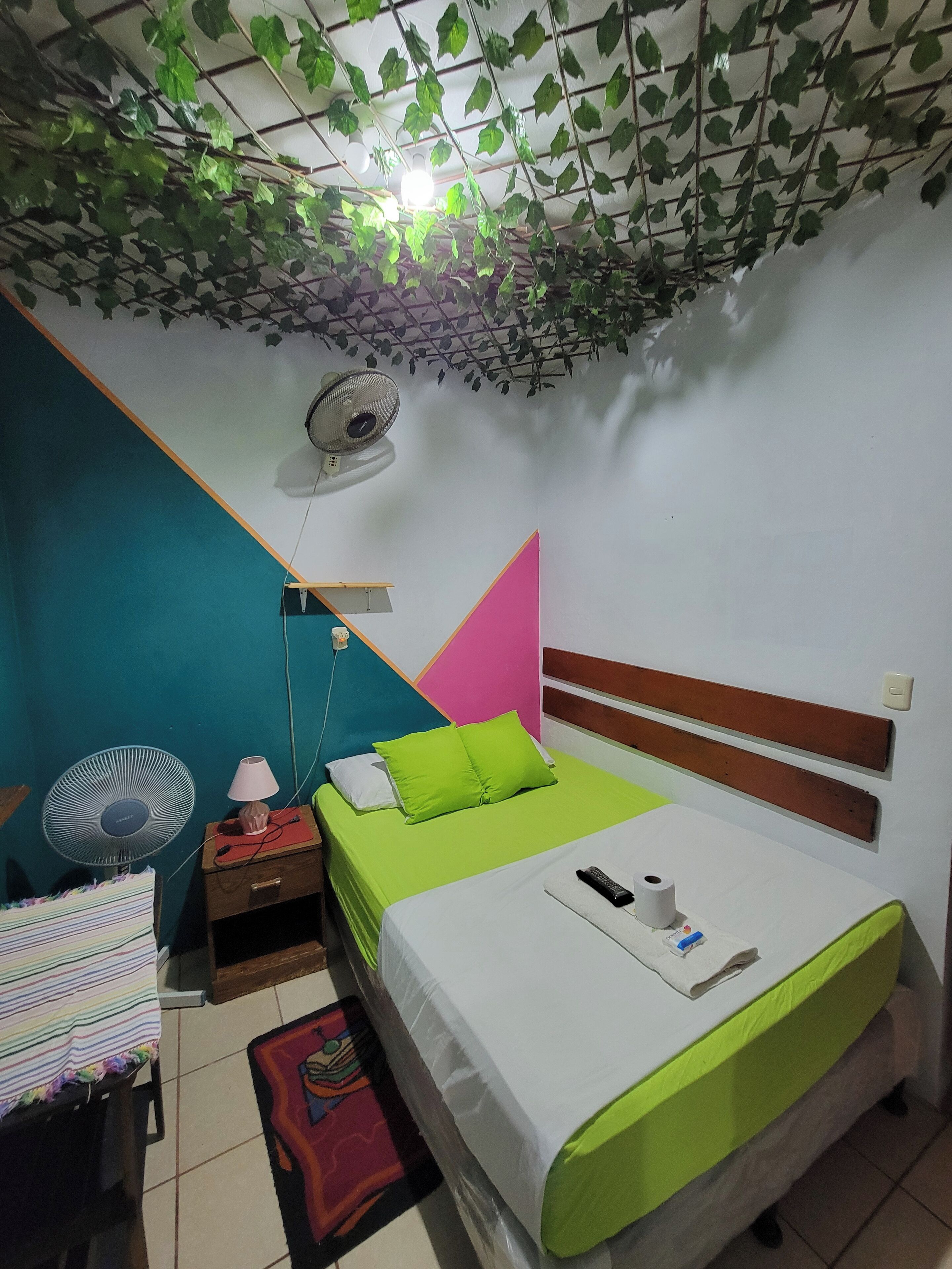 A bedroom with a bed, bedside table, lamp, and a ceiling fan.