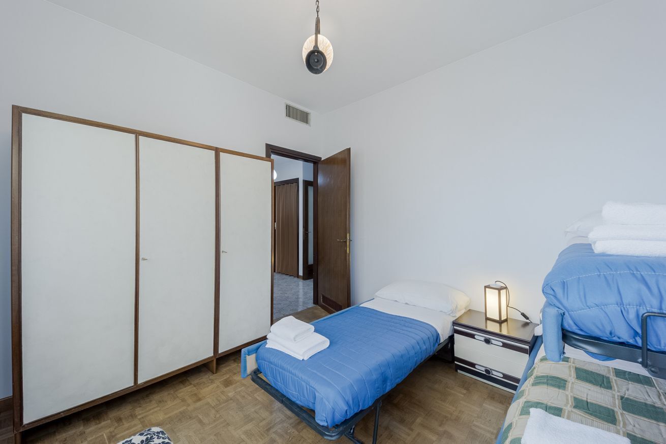 A bedroom with a bed, a nightstand, a wardrobe, and a mirror.