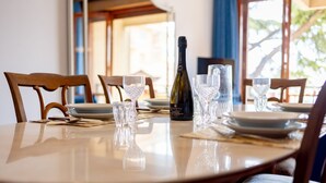 A dining table set with plates, glasses, and a bottle of wine. - GuestHost - Cozy apartment of about 110 square meters, able to accommodate up to 5 people, located on the 2nd floor of a building with lift and garage.The apartment has an enchanting view of the sea and the marina, surrounded by the greenery of Villa Orm (Sanremo)