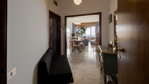 A hallway leading to a dining area with a bench, a table, and a cabinet. - GuestHost - Cozy apartment of about 110 square meters, able to accommodate up to 5 people, located on the 2nd floor of a building with lift and garage.The apartment has an enchanting view of the sea and the marina, surrounded by the greenery of Villa Orm (Sanremo)