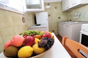 A kitchen with a fruit bowl on the counter, a refrigerator, and a sink.