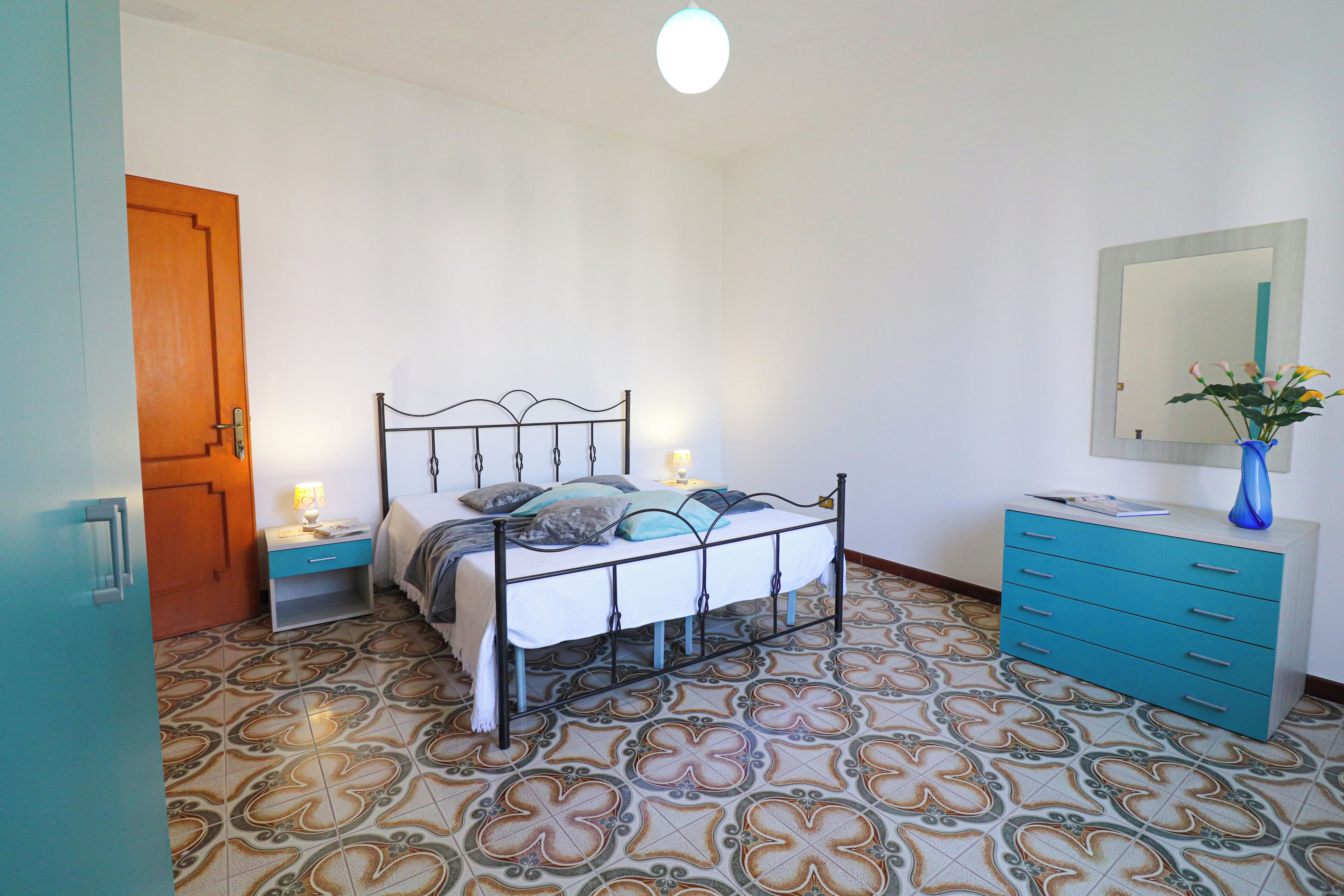 A bedroom with a bed, bedside tables, a dresser, and a mirror.