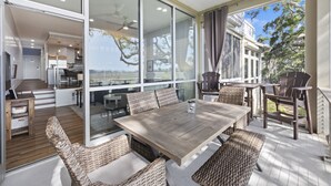 Tilava patio, jossa on puinen pöytä ja punottuista materiaaleista valmistetut tuolit, ja josta avautuu kaunis maisema.