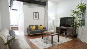 A living room with a sofa, a coffee table, a TV, and a plant.
