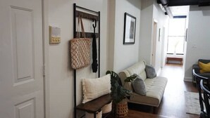 A living room with a sofa, a bench, a wall-mounted rack, and a hanging bag.