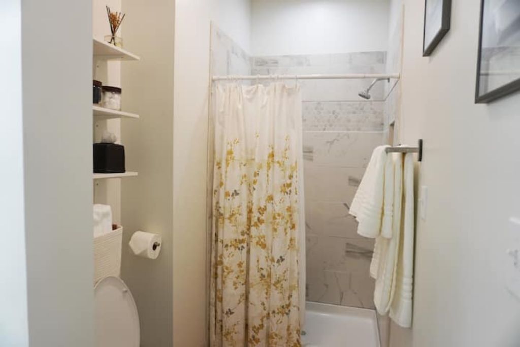 Een badkamer met toilet, douche en handdoekhouder.