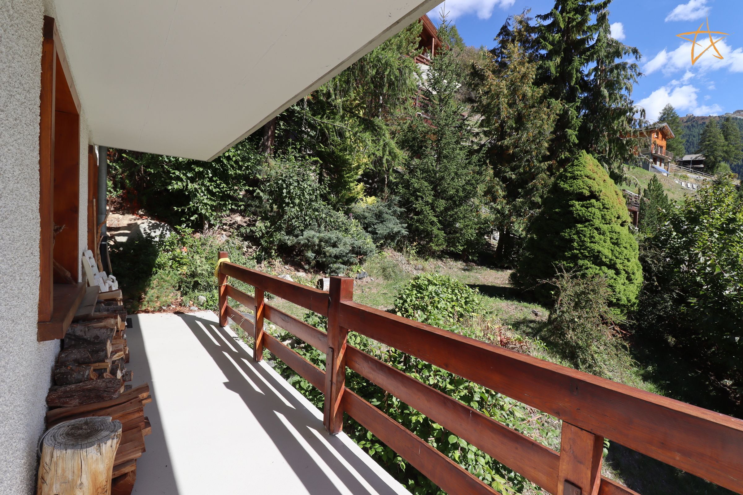 A balcony with a wooden railing overlooking a forested hillside.